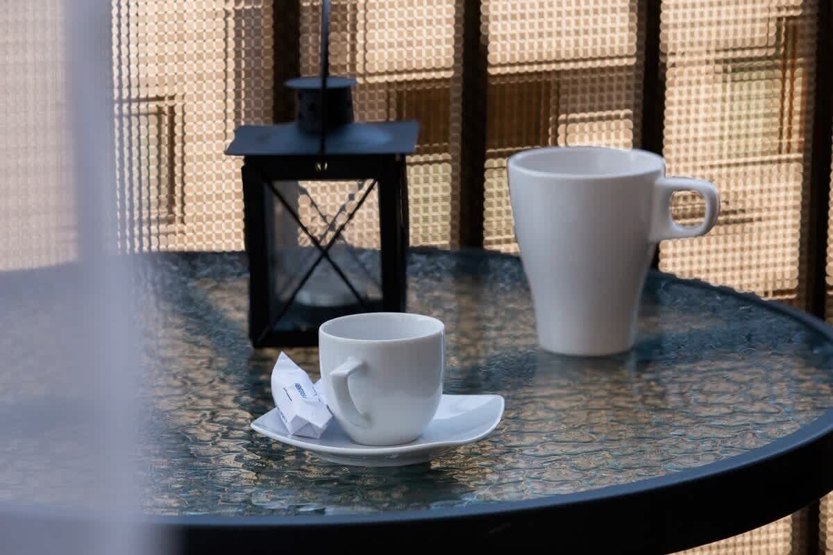 Ein runder Tisch mit einer weißen Tasse und einem Untertasse, einer schwarzen Laterne und einer weißen Packung darauf.
