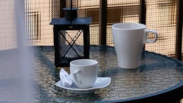 Ein runder Tisch mit einer weißen Tasse und einem Untertasse, einer schwarzen Laterne und einer weißen Packung darauf.