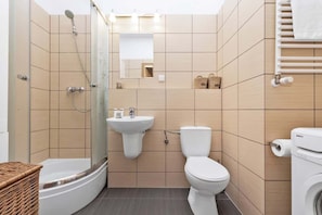 A modern bathroom with a shower, sink, toilet, and a built-in washing machine.