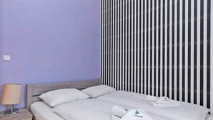 A hotel room with a bed, a nightstand, a lamp, and a striped wall.