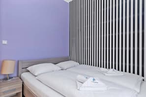 Ein Hotelzimmer mit einem Bett, einem Nachttisch, einer Lampe und einer gestreiften Wand.