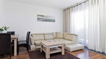 Ein modernes Wohnzimmer mit einer Eckcouch, einem Couchtisch aus Holz und einem Essbereich mit Tisch und Stühlen.