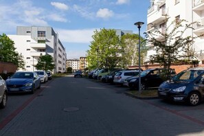A row of parked cars along a paved street in a residential area with modern buildings and trees.