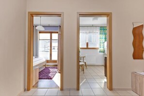 A modern apartment with a kitchen, dining area, and a bedroom with a bed and a purple rug.