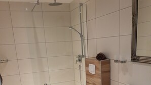 A modern bathroom with a shower, toilet, and sink. - Apartment with kitchen AND breakfast (Grafenhausen)