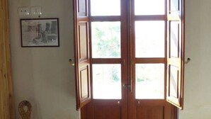 Une pièce avec une porte en bois dotée de panneaux de verre, une chaise en osier et un tableau encadré accroché au mur.