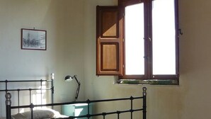 Une pièce avec un lit, un bureau, une fenêtre et un tableau au mur.