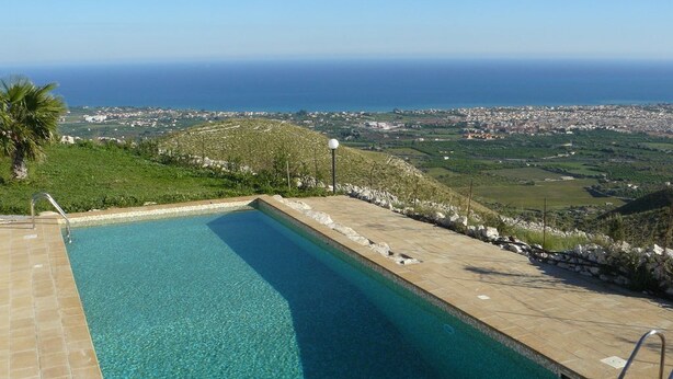 Une piscine offrant une vue dégagée sur l’océan et sur le paysage urbain au loin.
