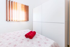 Ein Hotelzimmer mit Bett, Fenster mit Jalousien und einem Kleiderschrank.