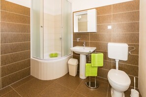 Ein Badezimmer mit Dusche, Waschbecken, Toilette und einer Duschkabine aus Glas.