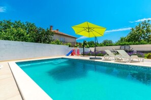 A swimming pool with a yellow umbrella, lounge chairs, and a slide. - Apartment Janko N2 (Medulin)