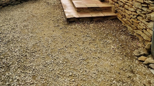 Ein Steingebäude mit einem Kiesweg, der zu einer Holztür führt.