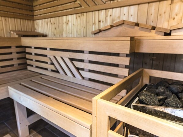 Una sauna con bancos de madera y una bandeja de piedra.