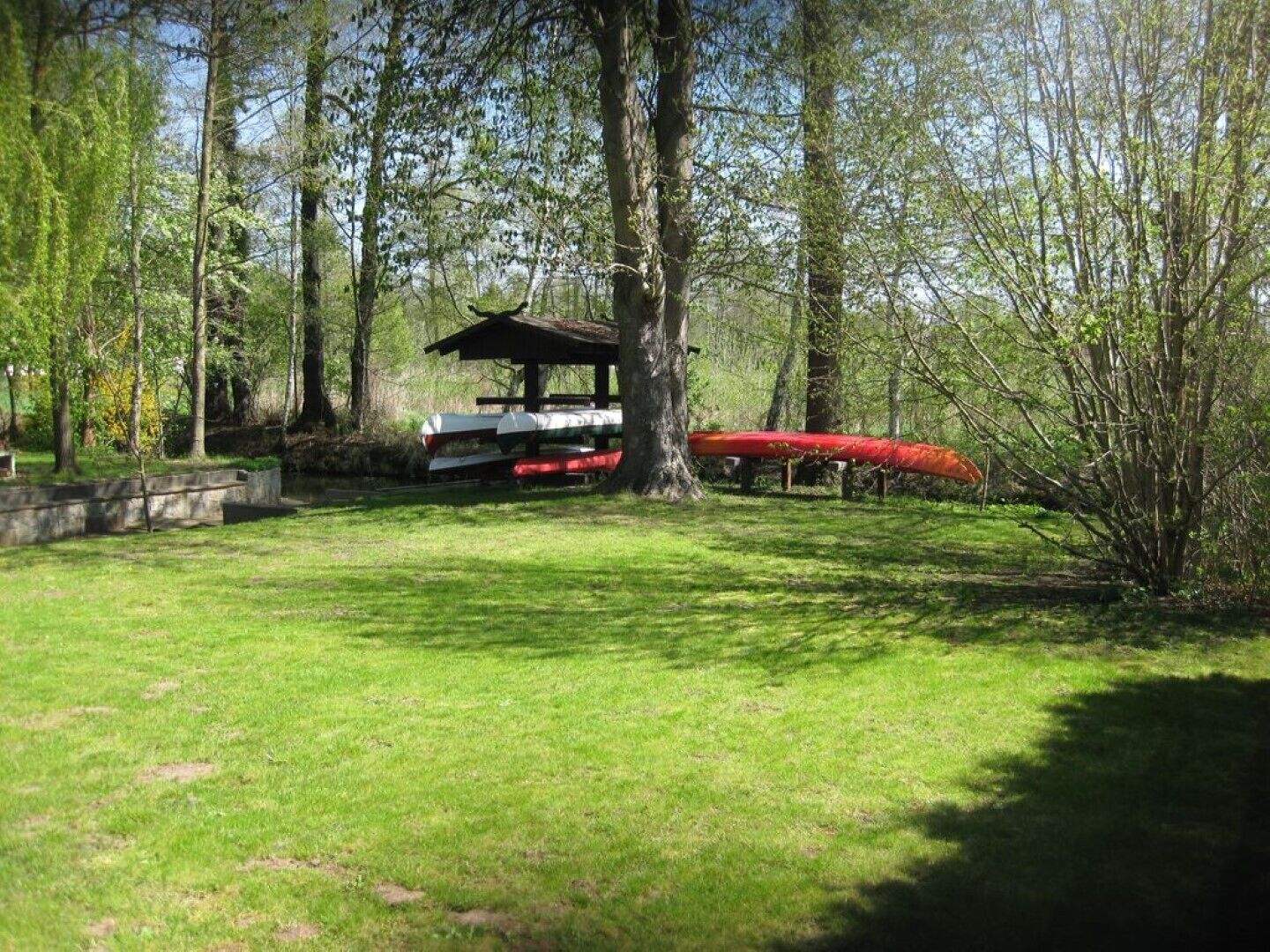 A park with a picnic shelter, a canoe, and a grassy area.