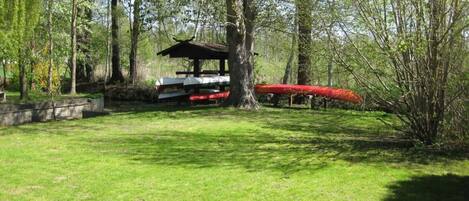 A park with a picnic shelter, a canoe, and a grassy area.