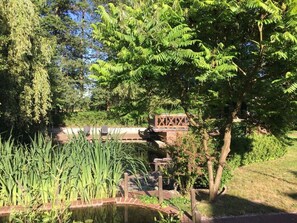 Un jardin paisible avec un étang, une végétation luxuriante et un pont en bois.