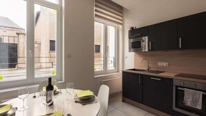 A modern kitchen with a dining area, large windows, and a view of the outside.