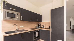 A modern kitchen with dark cabinets, a microwave, a sink, and a stove.