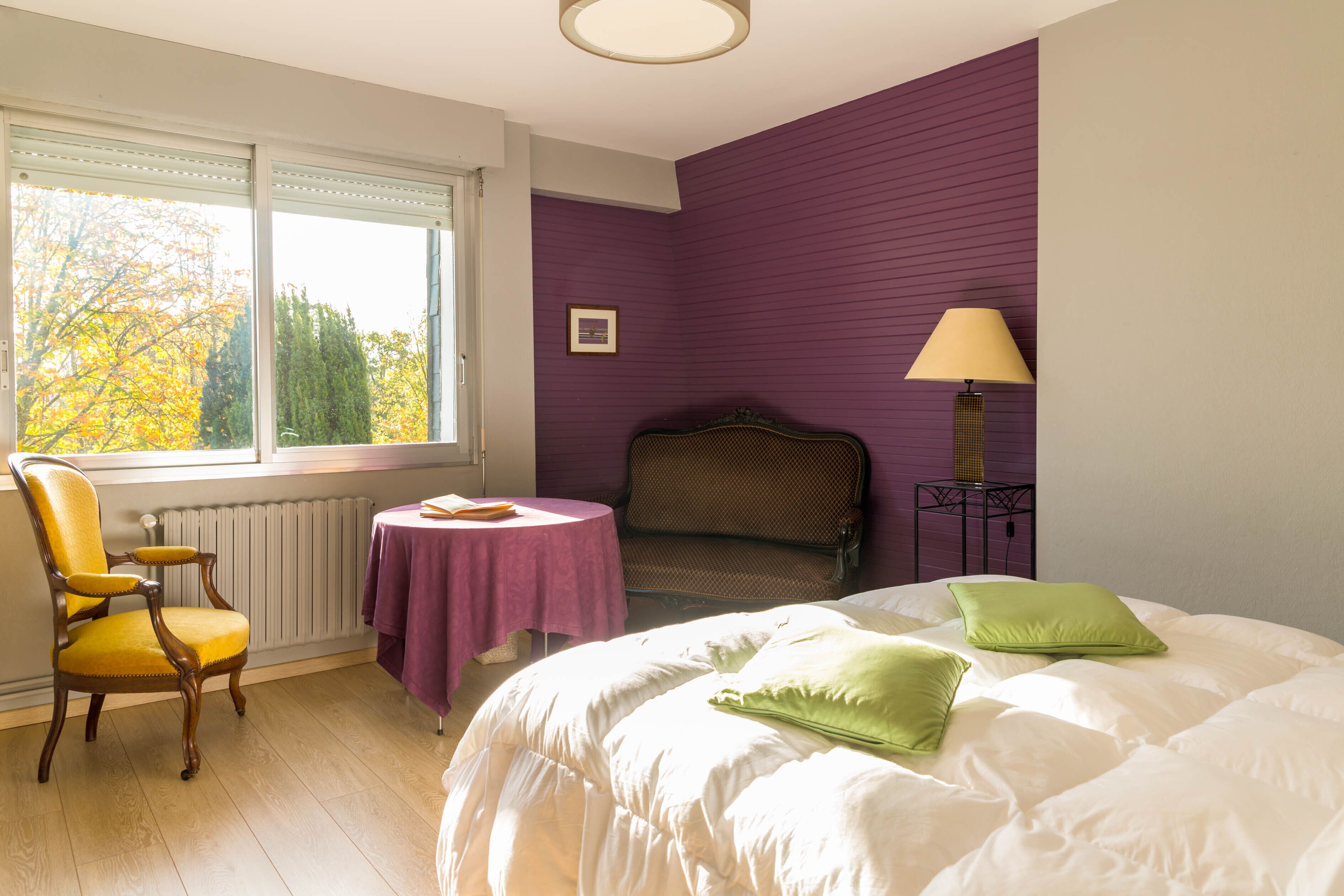 Une chambre à coucher avec un lit, une chaise, une table et une lampe.