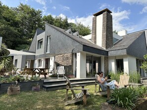 A modern house with a stone chimney, a covered patio, and a garden with potted plants. - La Maison de l'Orbière (Forcé)