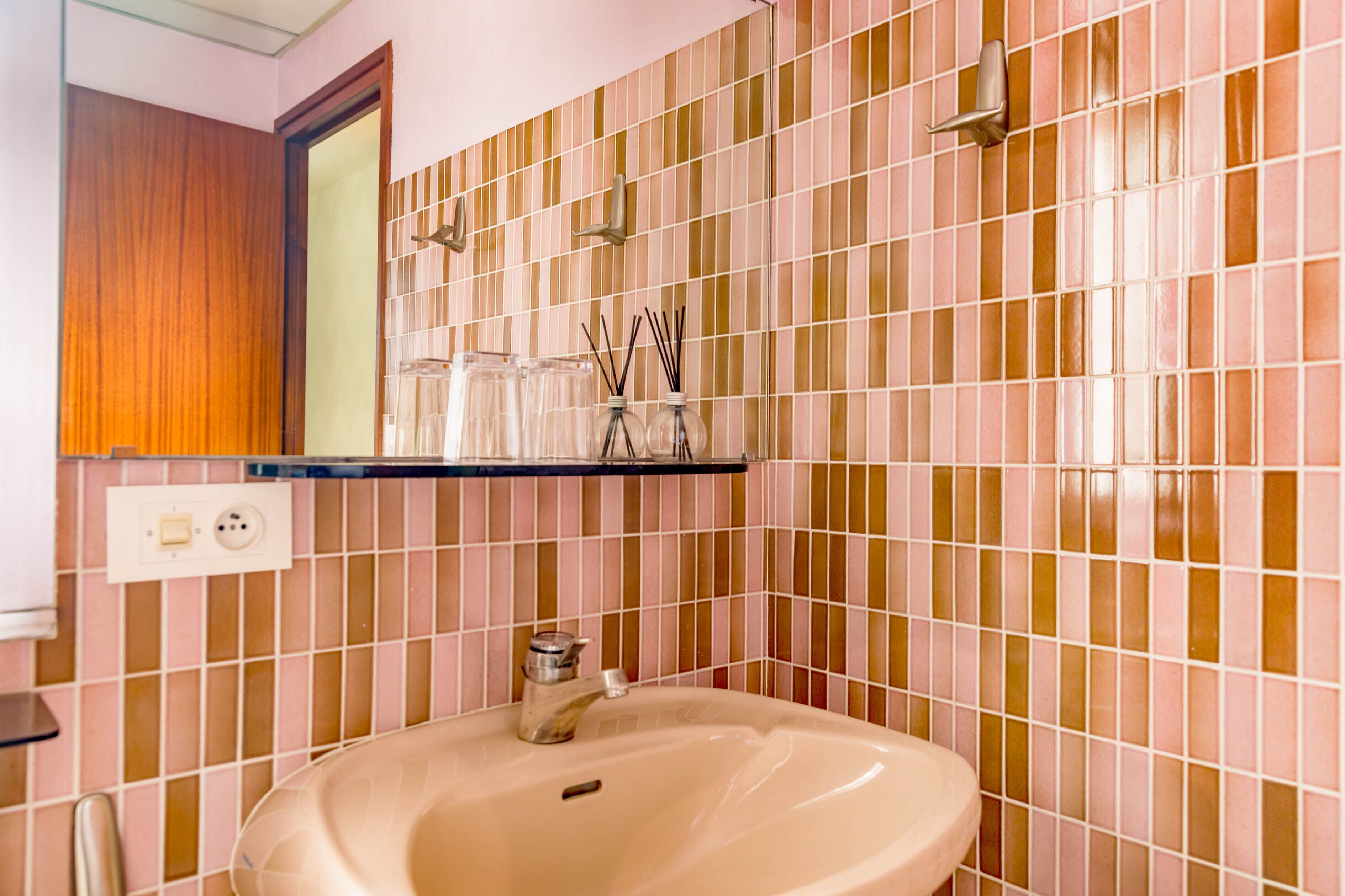 Un bagno con lavandino, specchio e pareti piastrellate.
