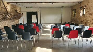 A conference room with rows of chairs, a projector screen, and a stone wall.