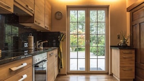 Eine moderne Küche mit Holzausstattung, einer schwarzen Arbeitsplatte und einem großen Fenster mit Blick auf Grünflächen.
