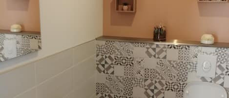 A bathroom with a white sink, a toilet, and patterned tiles on the walls.