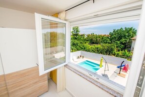 A balcony with a swimming pool, a view of greenery, and a clear sky. - Spacious Apartment Janko (Medulin)
