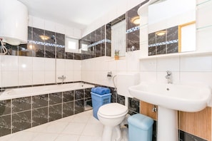 A modern bathroom with a bathtub, toilet, and sink. - Affordable Janko Apartment (Medulin)