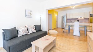 A modern living room with a grey sofa, a wooden coffee table, and a kitchen in the background. - Affordable Janko Apartment (Medulin)