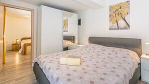 A bedroom with a bed, bedside table, and a wall-mounted TV. - Affordable Janko Apartment (Medulin)