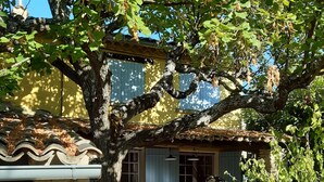 Une porte en pierre surmontée d’une clôture en bois, un mur de pierre et un bâtiment doté d’un toit en tuiles et de fenêtres.