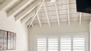 A bedroom with a bed, a ceiling fan, a window with blinds, and wall decor.