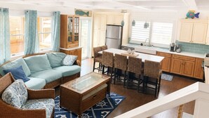 A modern kitchen with a central island, bar stools, and a dining table.