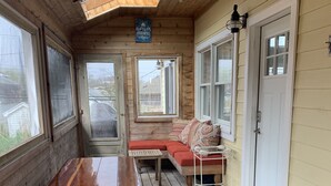 A wooden deck with a picnic table and benches, a covered seating area, and a door with a 'HELLO' mat.