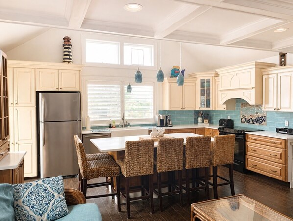 A kitchen with a central island, bar stools, and a refrigerator.