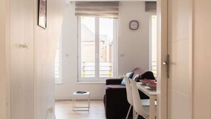 A corridor leading to a dining area with a window, a clock, and a small table. - ★★★ Bright one-bedroom apartment in downtown Voltaire with courtyard ★★★ (Saint-Quentin)