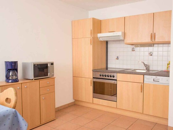 Une cuisine de taille réduite, dotée de meubles en bois, d’un four à micro-ondes, d’une cuisinière et d’un évier.