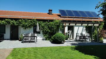 Ein Haus mit Ziegeldach, Solaranlage und Terrasse mit Gartenmöbeln.