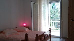 Un dormitorio con una cama de madera, una lámpara de noche, aire acondicionado y vistas al exterior a través de una puerta.