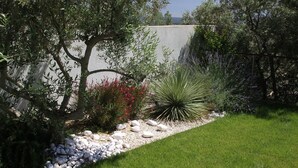 A landscaped garden with a variety of plants, a rock bed, and a well-maintained lawn. - Air-conditioned Provençal villa in a quiet location with magnificent views. (EGUILLES)