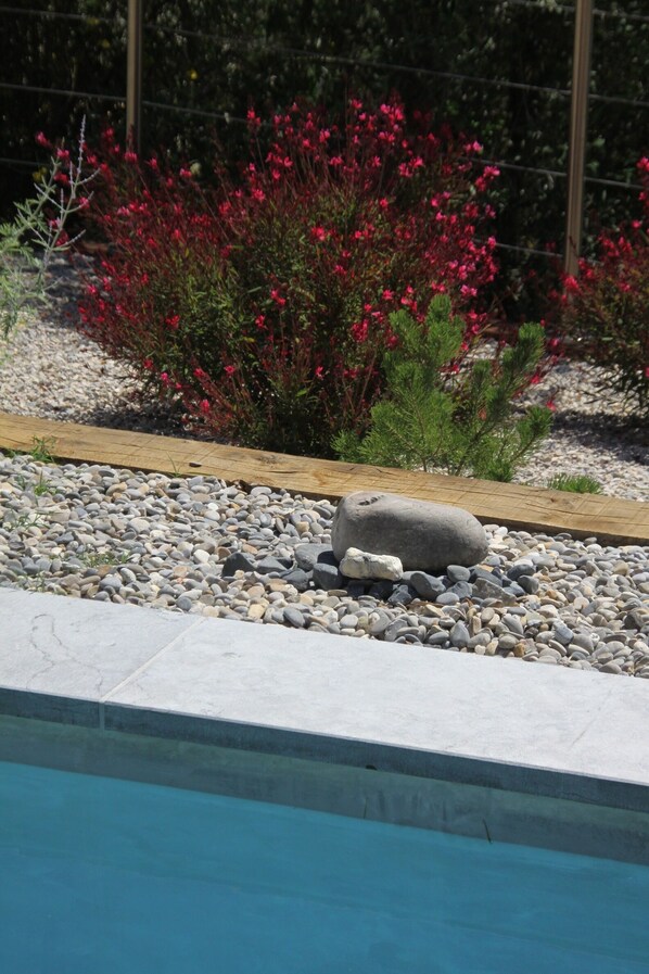 A pool with a pebble border and a wooden deck. - Air-conditioned Provençal villa in a quiet location with magnificent views. (EGUILLES)