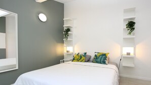 A modern bedroom with a large bed, white walls, and built-in shelving with plants. - Air-conditioned Provençal villa in a quiet location with magnificent views. (EGUILLES)