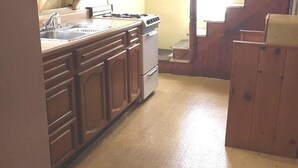 Een keuken met houten kastjes, een fornuis en een spoelbak.