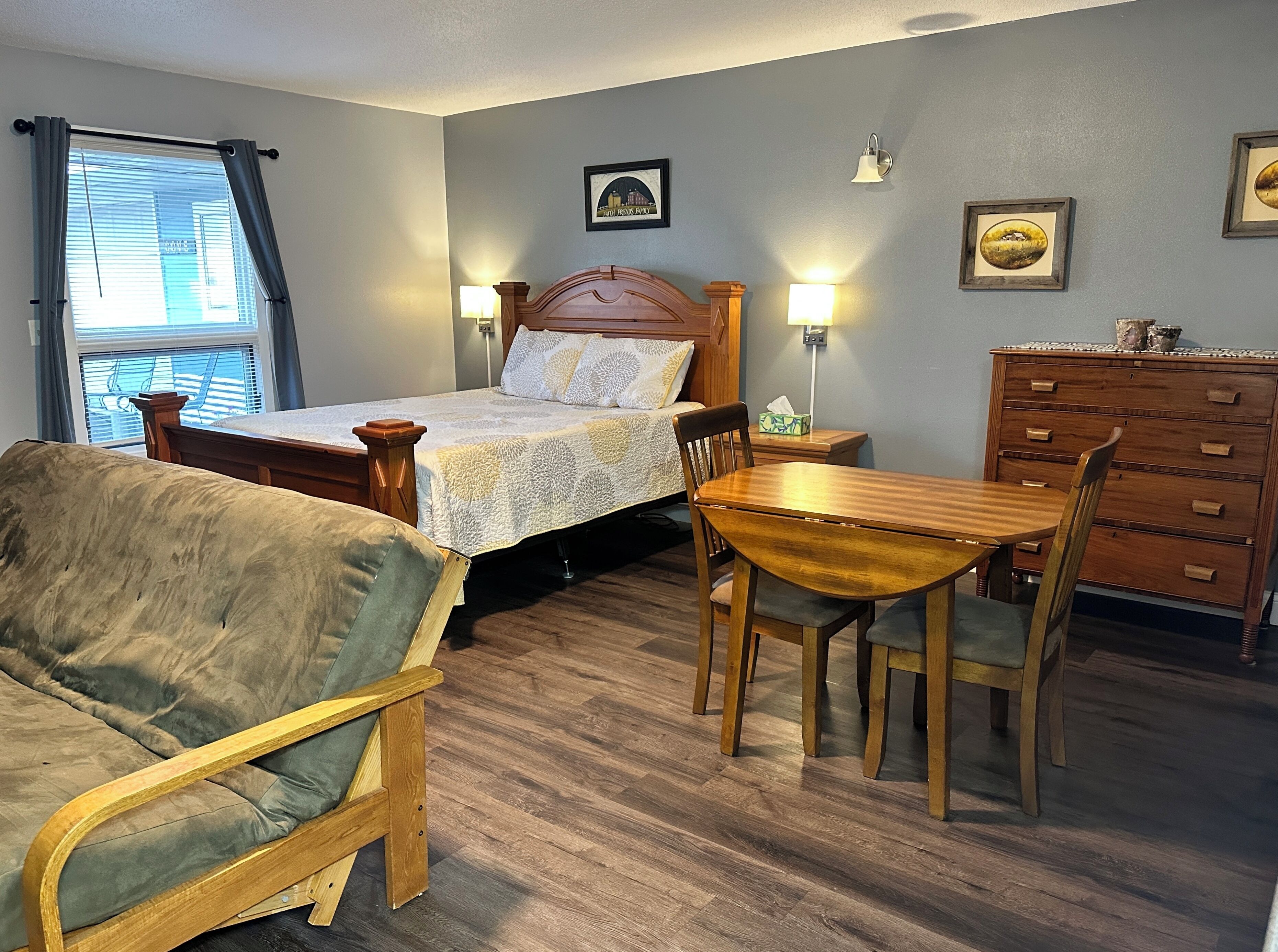 Quarto com cama, mesas de cabeceira, penteadeira, cadeira de madeira e mesa de jantar.