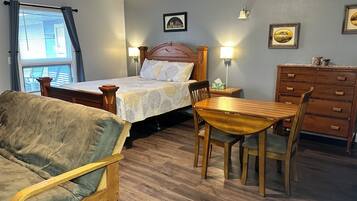 Quarto com cama, mesas de cabeceira, penteadeira, cadeira de madeira e mesa de jantar.