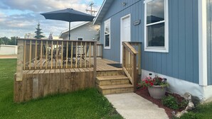 A residential house with a wooden deck, a covered patio, and a front porch with steps leading to the entrance. - Pelican Motel (Pelican Rapids)
