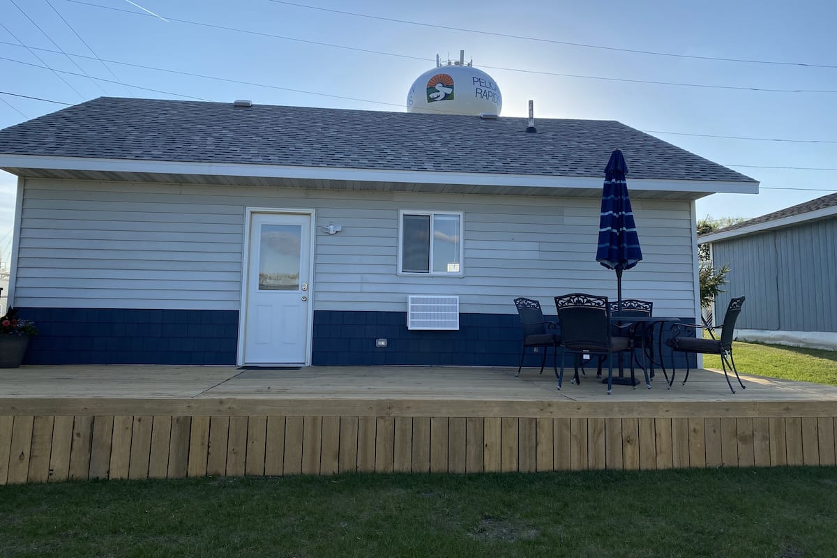 A small building with a covered patio area, a door, and a small window.