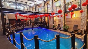 Ein überdachter Pool mit Seilabsperrung, umgeben von Steinmauern und roten Laternen.
